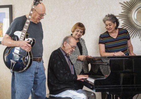 Senior people watching senior man playing piano
