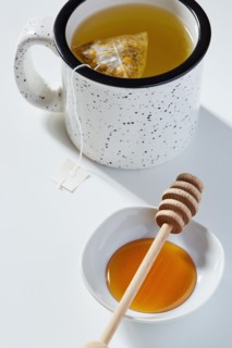 Cup of tea, honey dipper and bowl of honey