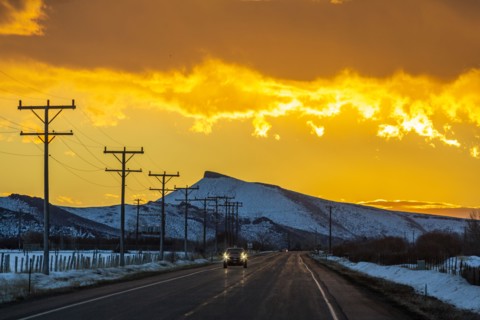 Car on road under dramatic sky at sunrise