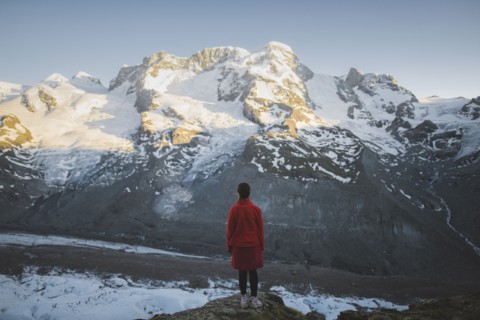 Woman standing on rock by Gorner Glacier in Valais, Switzerland
