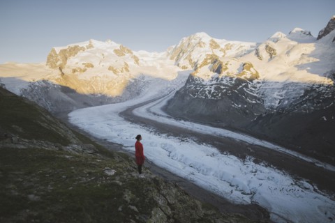 Woman standing on rock by Gorner Glacier in Valais, Switzerland