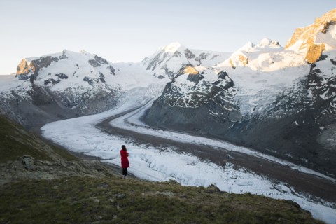 Woman standing on rock by Gorner Glacier in Valais, Switzerland