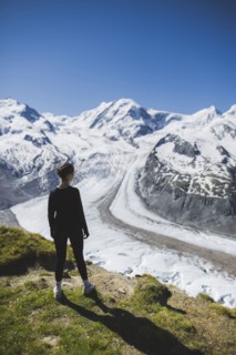 Woman standing on grass by Gorner Glacier in Valais, Switzerland