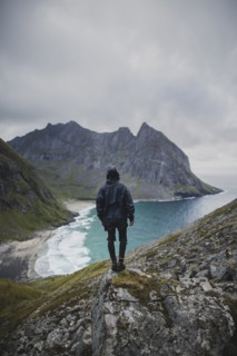 Man standing on rock by Kvalvika Beach in Lofoten Islands, Norway