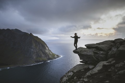 Man standing on cliff at Ryten mountain in Lofoten Islands, Norway
