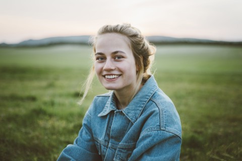 Smiling woman wearing denim jacket in field