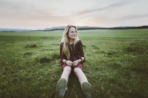 Smiling woman wearing dress sitting in field