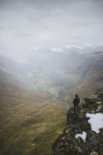 Man standing on Dalsnibba mountain overlooking valley in Geiranger, Norway