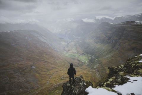 Man standing on Dalsnibba mountain overlooking valley in Geiranger, Norway