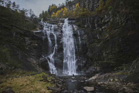 Person standing by Skjervefossen waterfall in Norway