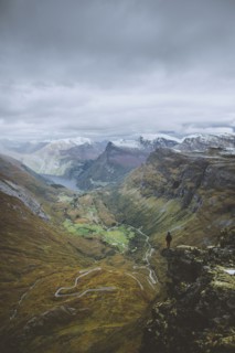 Man standing on Dalsnibba mountain overlooking valley in Geiranger, Norway