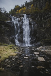 Person standing by Skjervefossen waterfall in Norway