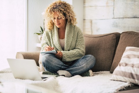 Smiling woman working with laptop on sofa