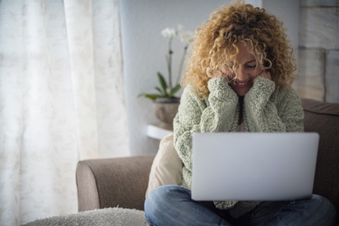 Smiling woman working with laptop on sofa