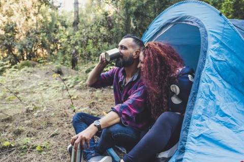 Smiling couple drinking by tent