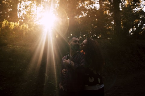 Smiling couple embracing by sunlight in forest