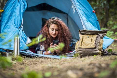 Woman lying in tent using smart phone