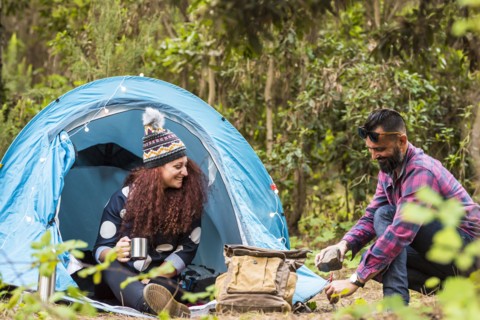 Man using rock to hammer tent peg