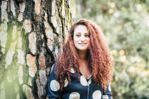 Smiling brown haired woman by tree