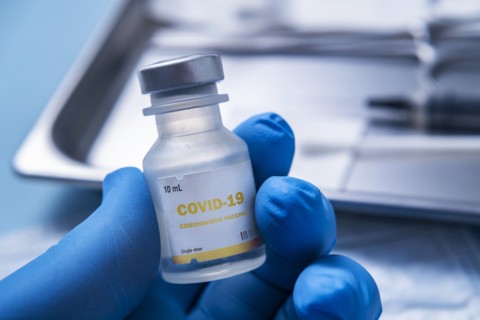 Close-up of gloved hand holding vial of Covid-19 coronavirus vaccine