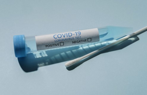 Covid-19 test vial and swab on blue background