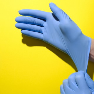 Senior woman putting on surgical gloves