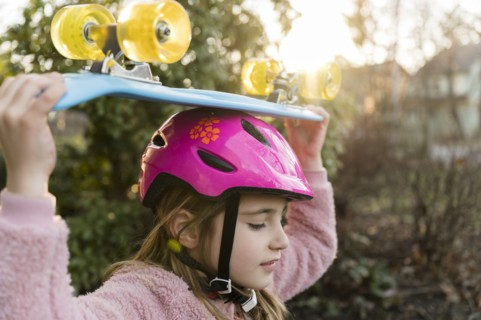 Girl carrying skateboard on head