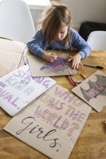 Girl coloring protest signs for women's march