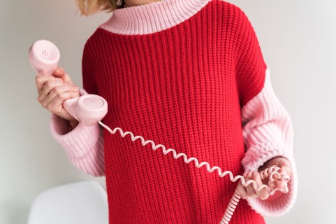 Woman holding vintage phone receiver with twisted cable