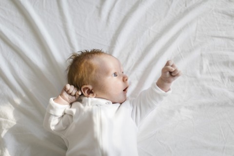 Baby boy (2-5 months) lying on bed