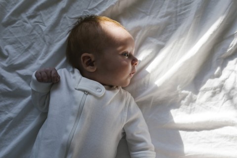 Baby boy (2-5 months) lying on bed
