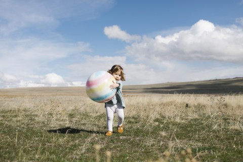 Girl (2-3) holding ball in open field