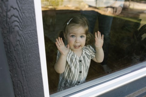 Girl (2-3) looking through window