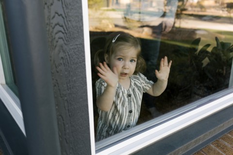 Girl (2-3) looking through window