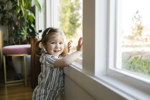 Girl (2-3) standing at window