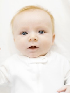 Portrait of baby boy (2-3 months) lying on bed