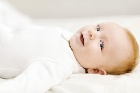 Portrait of baby boy (2-3 months) lying on bed