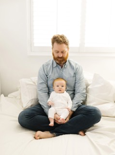 Father sitting on bed with baby boy (2-3 months)