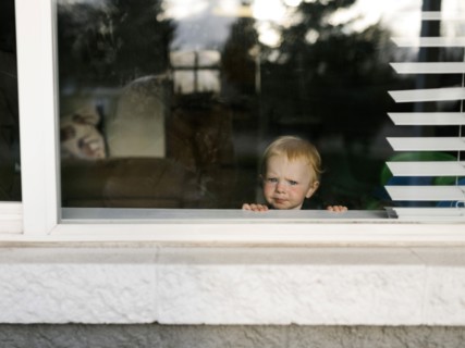 Girl (2-3) looking through window