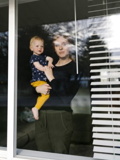 Mother holding daughter (2-3) and looking through window