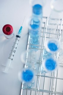 Overhead view of test tubes with blue liquid and syringe