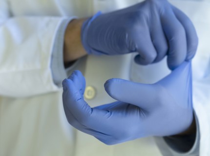Close-up of doctor putting on blue latex gloves