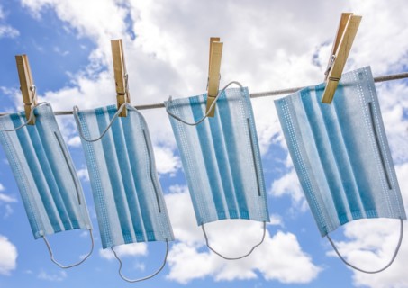 Row of surgical masks hanging on clothesline with sky in background
