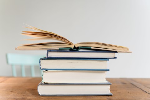 Open book on top of stack of books on desk