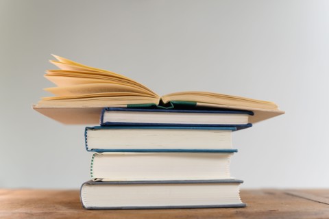 Open book on top of stack of books on desk