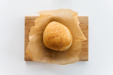 Fresh loaf of bread cooling on cutting board
