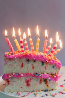 Slice of birthday cake with lit candles