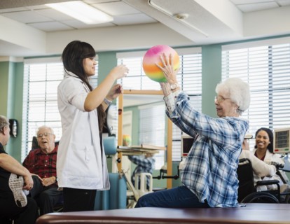 Senior woman exercising with therapist during physical therapy