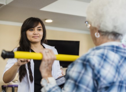 Senior woman exercising with therapist during physical therapy