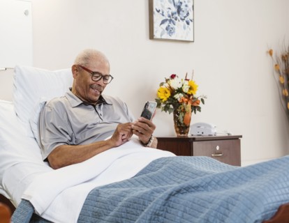 Senior man lying in bed and using smart phone